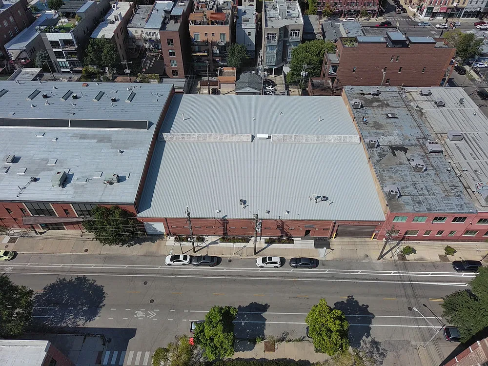 Front view of urban industrial warehouse with metal roof system serviced by Americanstruction