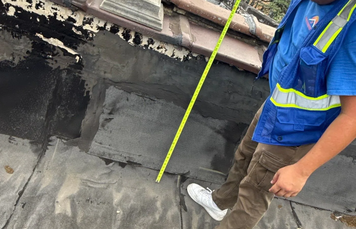 Americanstruction technician inspecting and measuring a commercial roof repair area