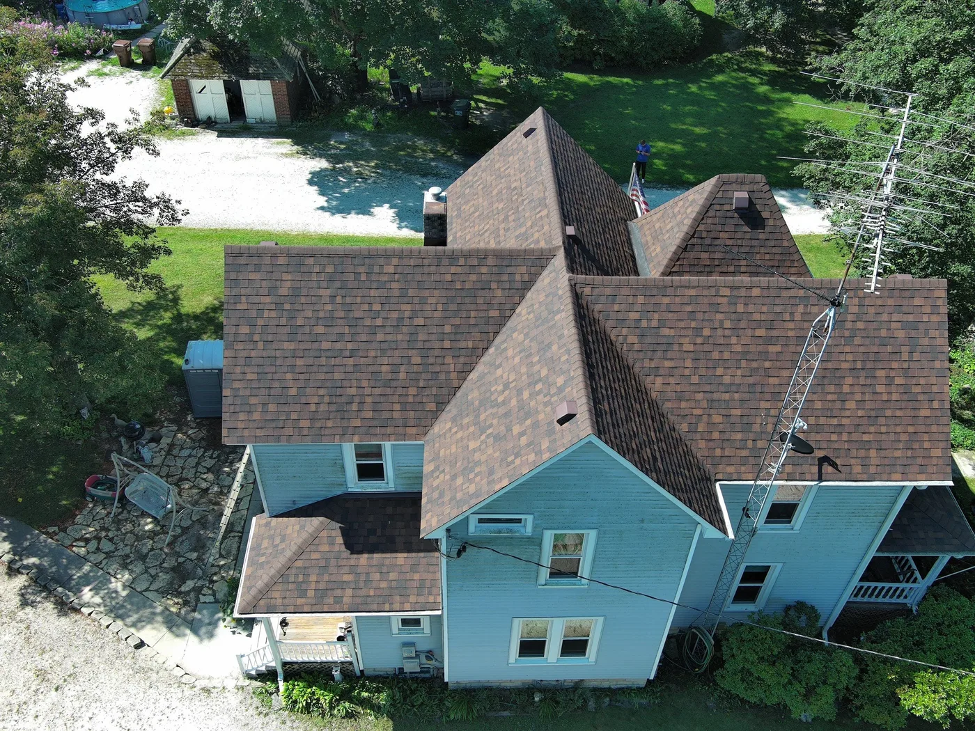 The Powell's Bonfield farmhouse with a new Owens Corning Duration architectural shingle roof in Brownwood and barn behind