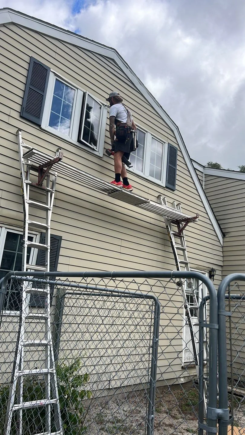 Americanstruction crew installing a second-story window from a plank